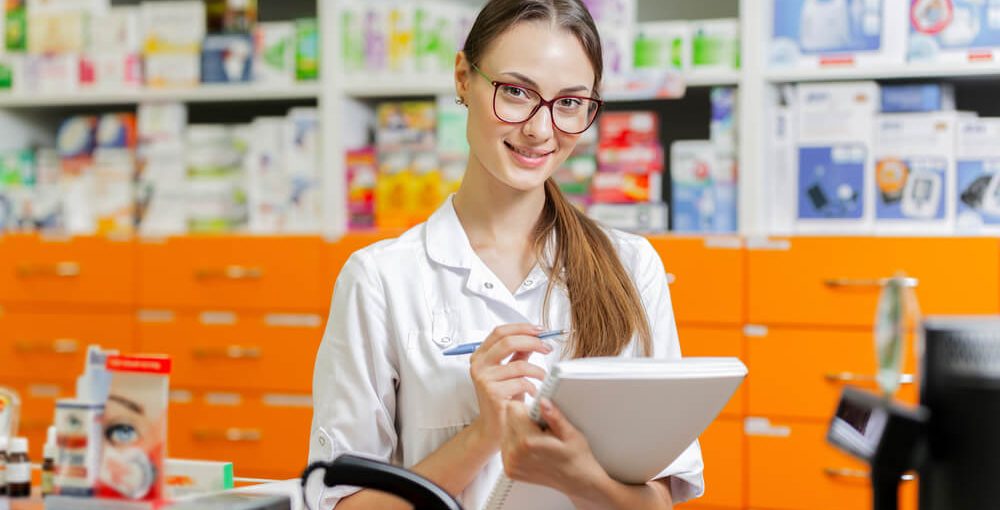 A young female pharmacy technician working behind a counter in a drug store