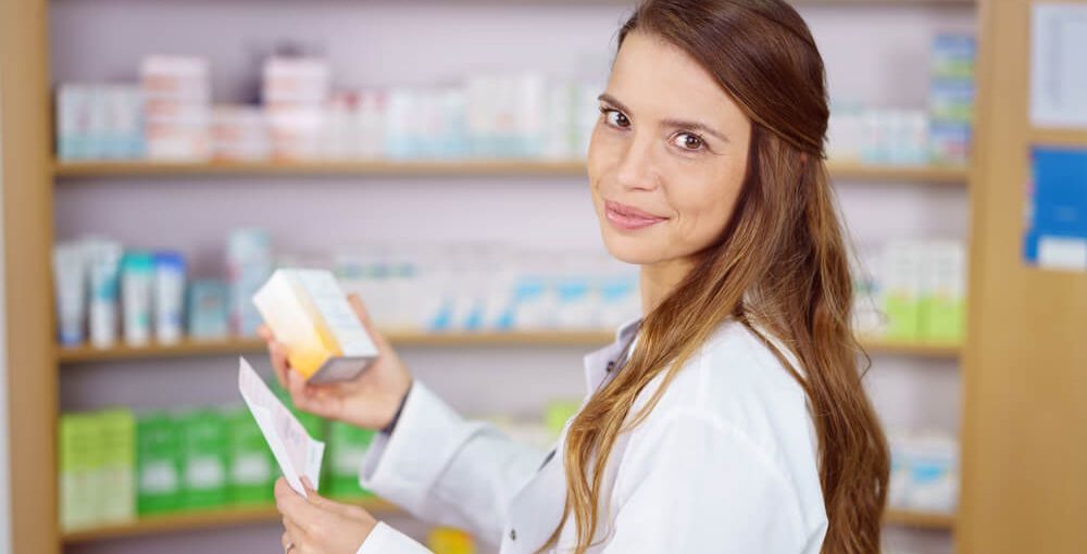 Pharmacy Technician Working in a drug store and holding a prescription