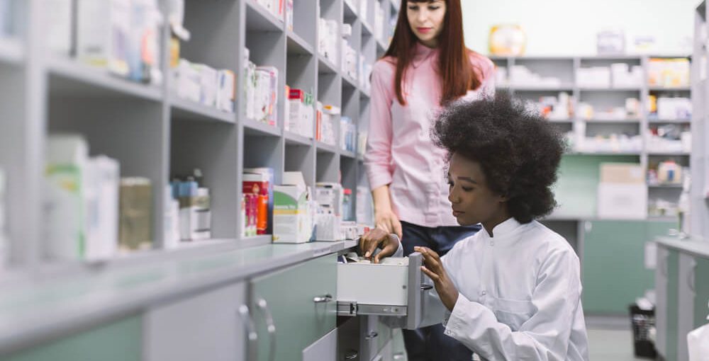 A pharmacy technician trainee working alongside a Pharmacist at the back of a retail pharmacy