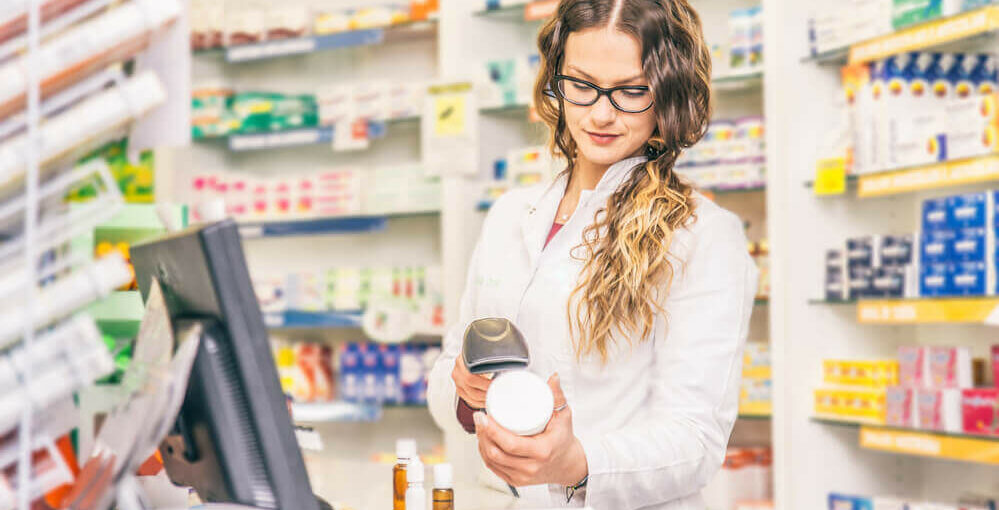 Pharmacy technician scanning prices of drug in a pharmacy setting